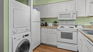 A compact kitchen with a washing machine, microwave, toaster, and stove. - A Place at the Beach (Atlantic Beach)