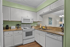 A kitchen with white cabinets, a microwave, a stove, and a dishwasher. - A Place at the Beach (Atlantic Beach)