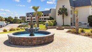 A hotel with a fountain, palm trees, and a parking lot. - A Place at the Beach (Atlantic Beach)