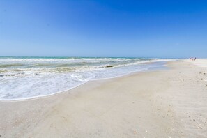 A beach with waves, a clear sky, and a few people in the distance. - A Place at the Beach (Atlantic Beach)