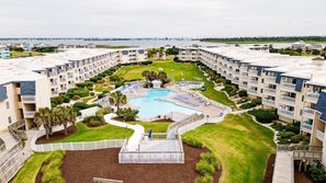 A hotel with multiple balconies, a central swimming pool, and a landscaped lawn. - A Place at the Beach (Atlantic Beach)