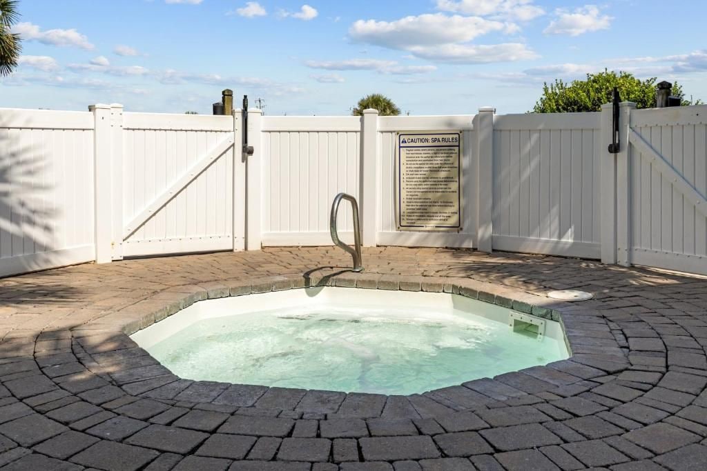A swimming pool with a white fence, a metal gate, and a caution sign.
