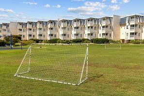 Un arco de fútbol en un campo de césped con una fila de edificios de apartamentos al fondo.