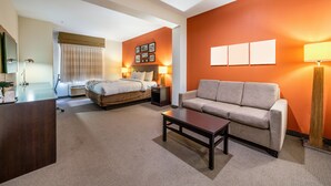 Une chambre d’hôtel avec un lit, un canapé, une table basse et un bureau.