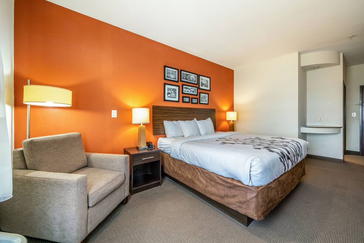 Une chambre d’hôtel avec un lit, un canapé, une table de chevet et un mur orné de tableaux.