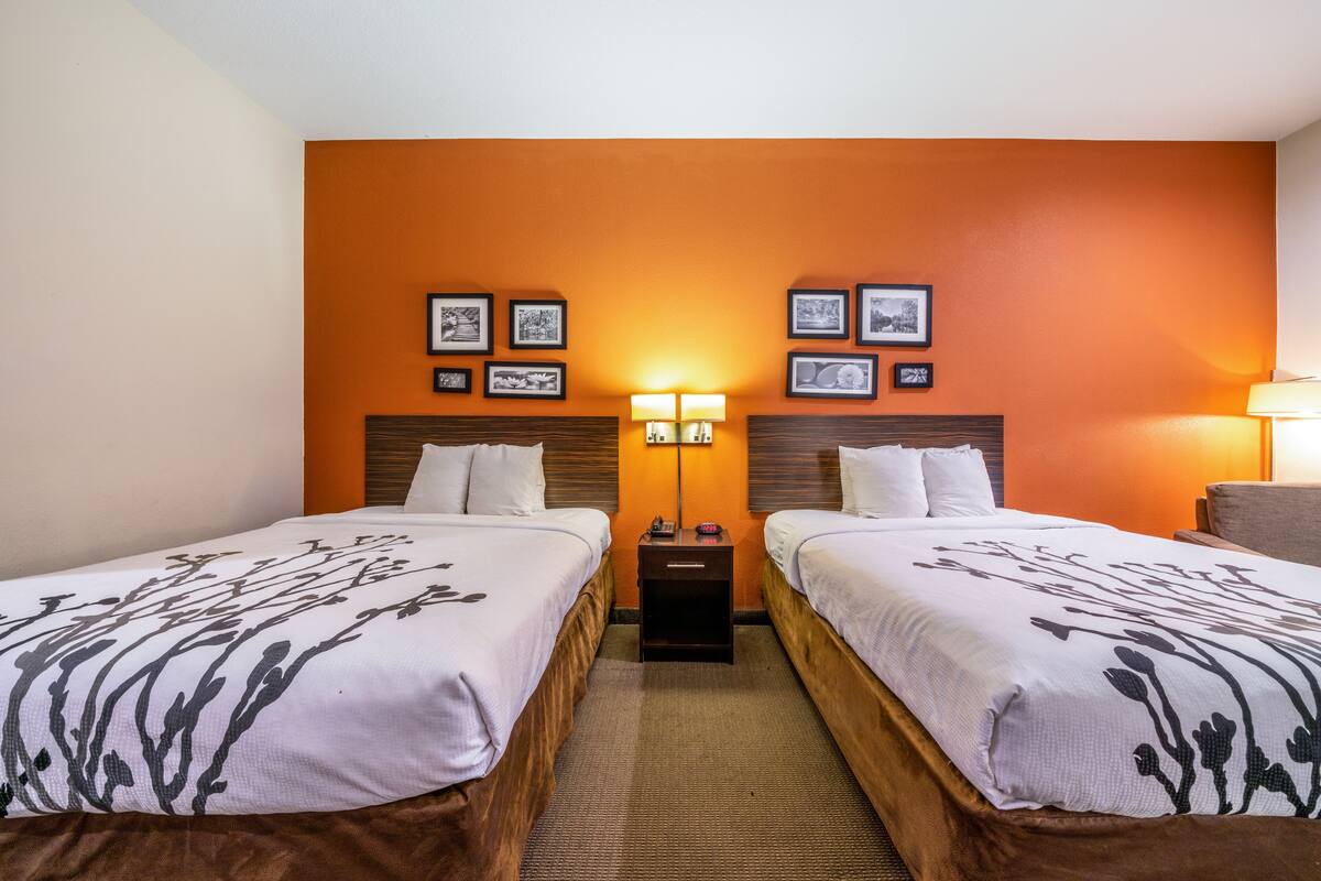 Une chambre d’hôtel avec deux lits, une table de chevet, une lampe et des tableaux encadrés au mur.