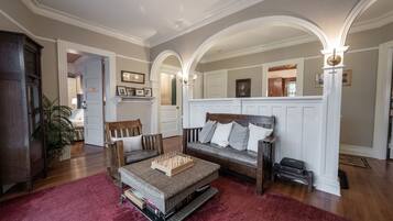 A living room with a wooden sofa, a coffee table, and a red rug. There is a wooden cabinet and a plant in the corner.