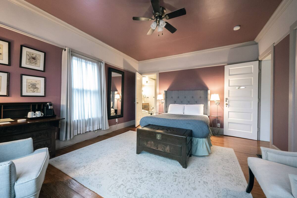 A spacious bedroom with a large bed, a ceiling fan, a dresser, and a nightstand.