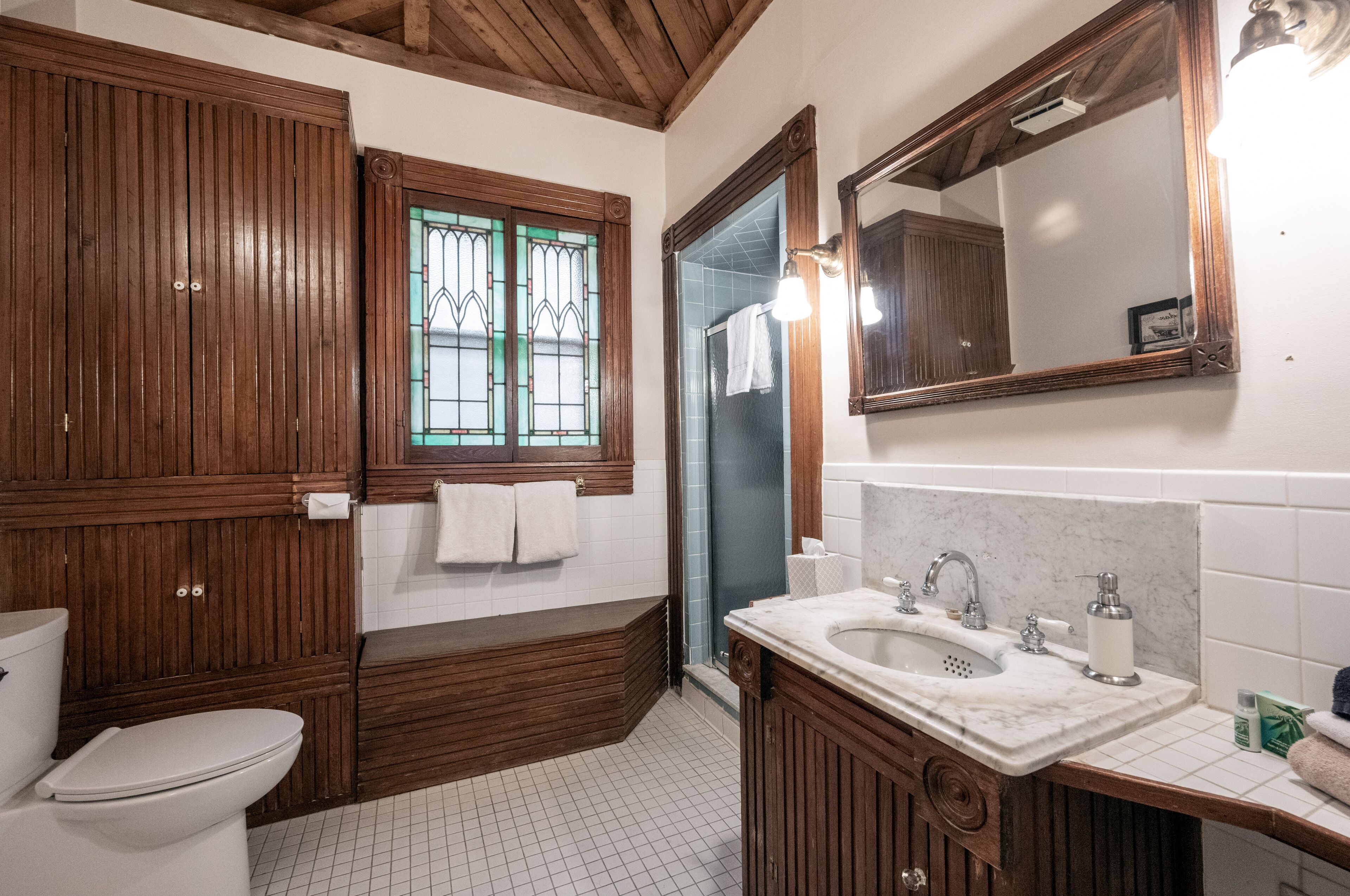 A bathroom with a wooden vanity, a sink, a mirror, and a toilet.