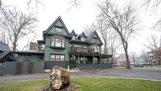 A large, green Victorian-style building with multiple stories and a prominent corner turret.