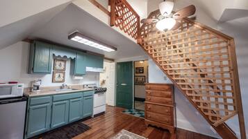 A kitchen with teal cabinets, a wooden staircase, and a ceiling fan.