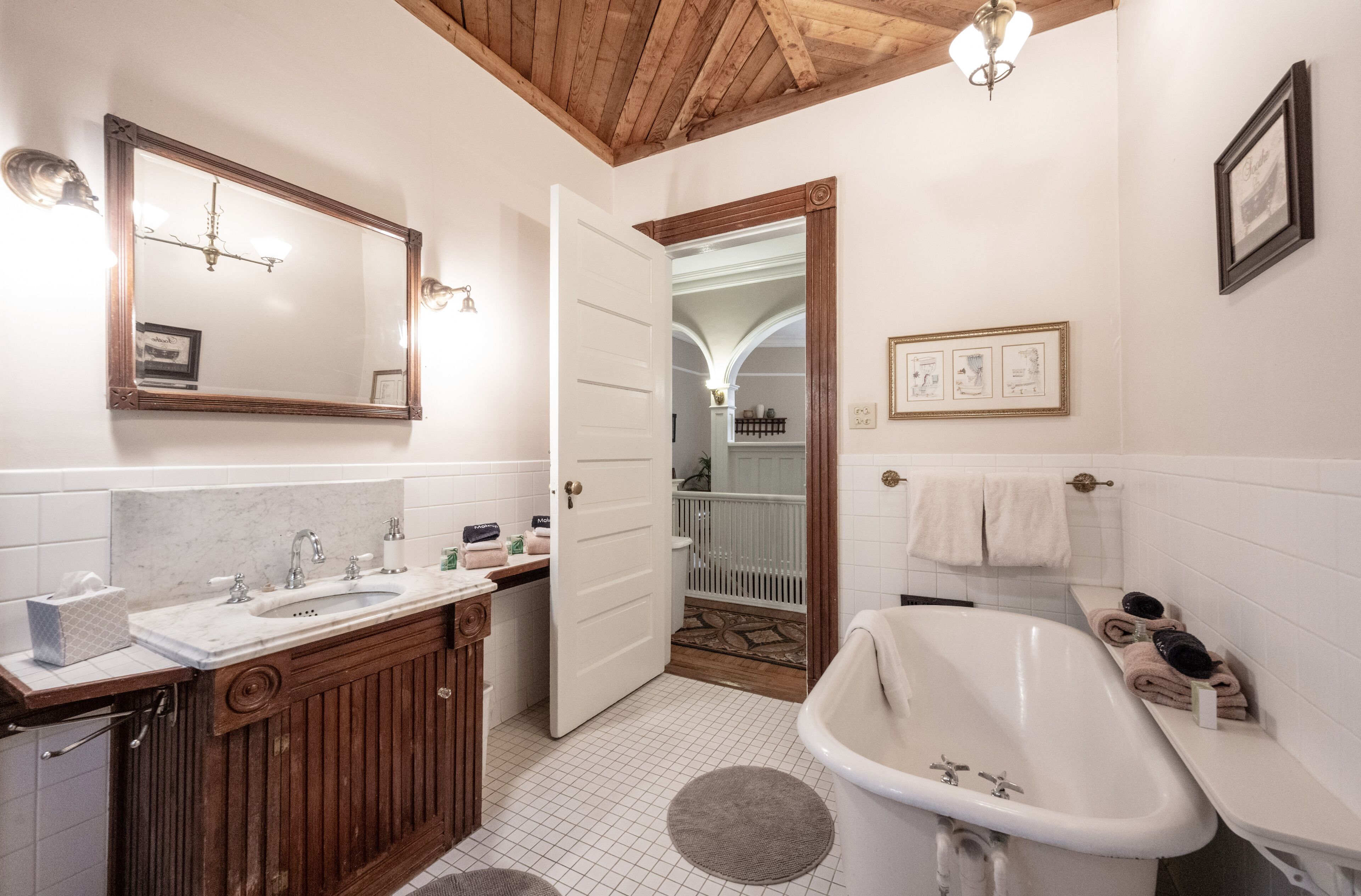 A bathroom with a wooden vanity, a white sink, a bathtub, and a mirror.
