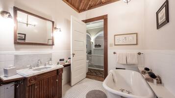A bathroom with a wooden vanity, a white sink, a bathtub, and a mirror.