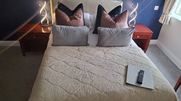 Un lit bien fait, recouvert d’une courtepointe matelassée, deux tables de chevet avec des lampes et un ordinateur portable posé sur le lit.