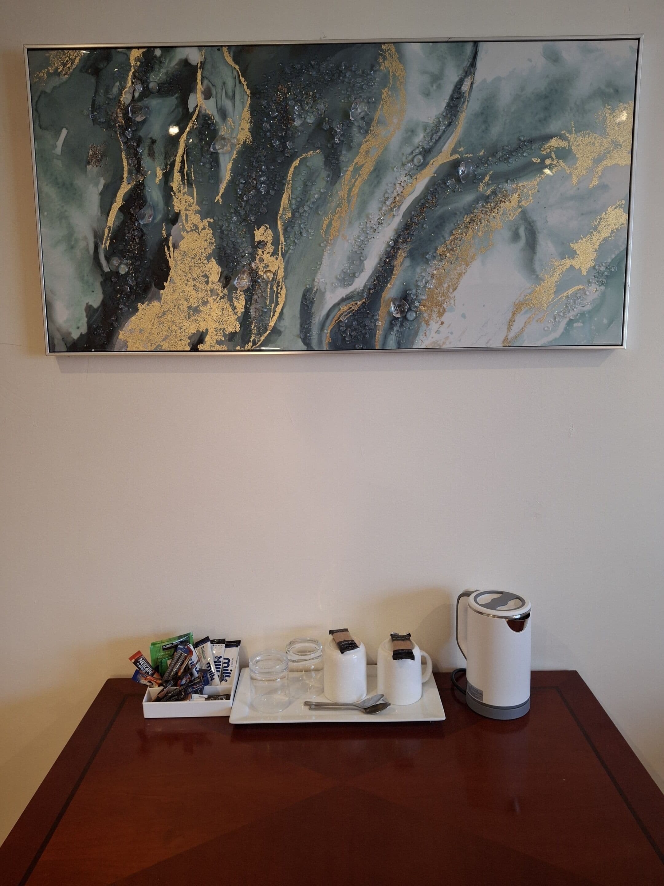 Une table sur laquelle se trouve un plateau contenant une cafetière, des tasses, une cuillère et une petite boîte de mouchoirs.