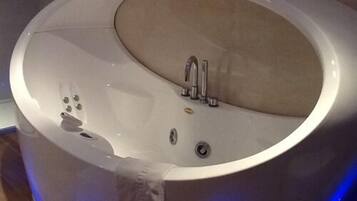 Una bañera moderna, de forma ovalada, con un solo grifo y una pequeña perilla de control.