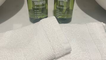 Two bottles of conditioner and shower gel on a bathroom counter.