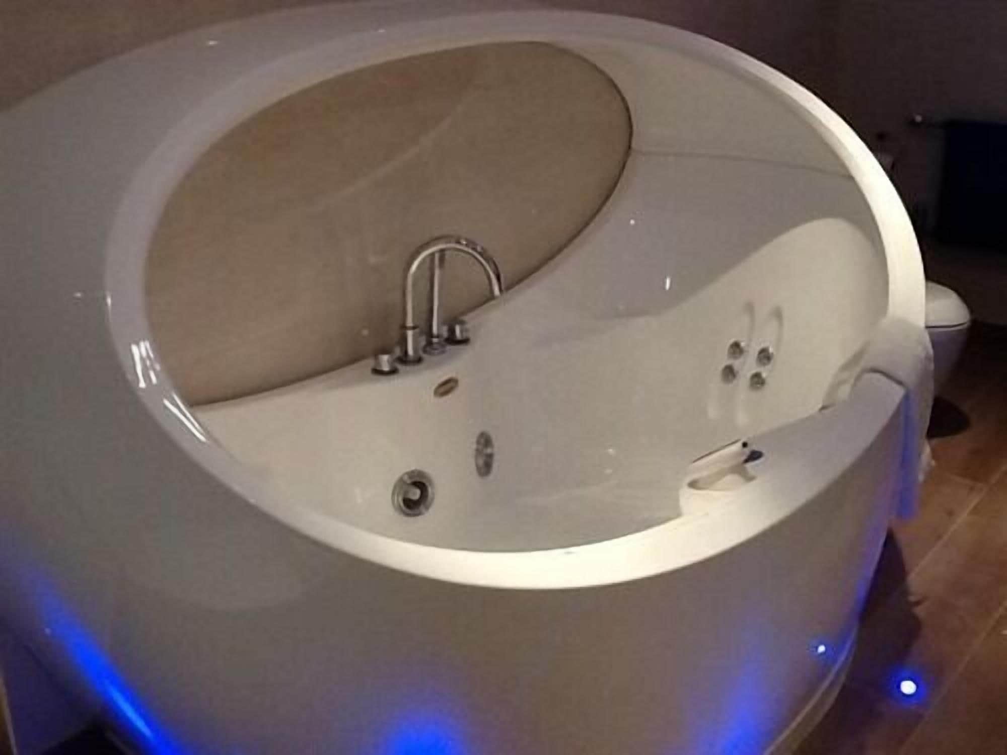 Una bañera moderna de forma ovalada con asiento incorporado y cabezal de ducha manual.