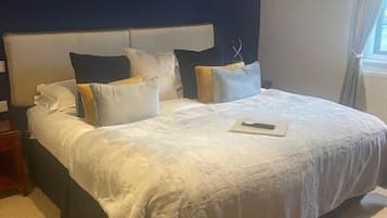 Una cama grande con cabecera, varias almohadas y una mesita de noche.