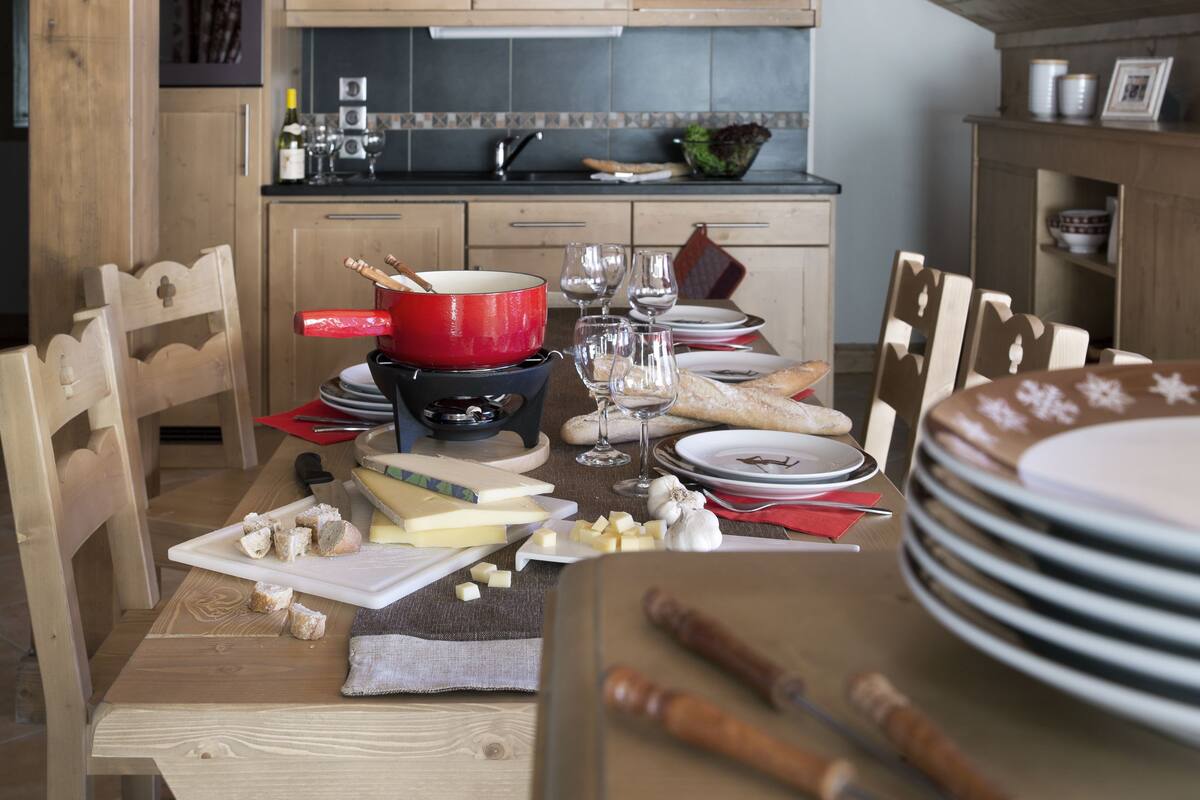 Een eethoek met een houten tafel, gedekt voor een maaltijd, omringd door houten stoelen.