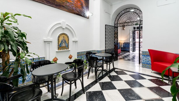 Un vestíbulo de hotel con piso a cuadros, paredes blanco y negro, un sofá rojo y un cuadro grande.