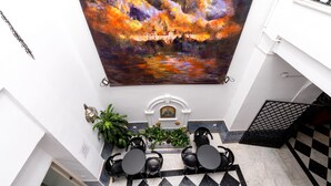 Un comedor con un mural, sillas negras y suelo de baldosas.