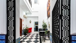 Un pasillo con piso a cuadros, un sofá rojo y un área de comedor con sillas y una mesa.