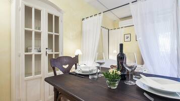 A dining table set with plates, glasses, and a bottle, a chair, and a cabinet with glass doors.