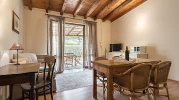 Una habitación acogedora con una mesa de comedor de madera, sillas de mimbre, un sofá y una cocina con electrodomésticos.