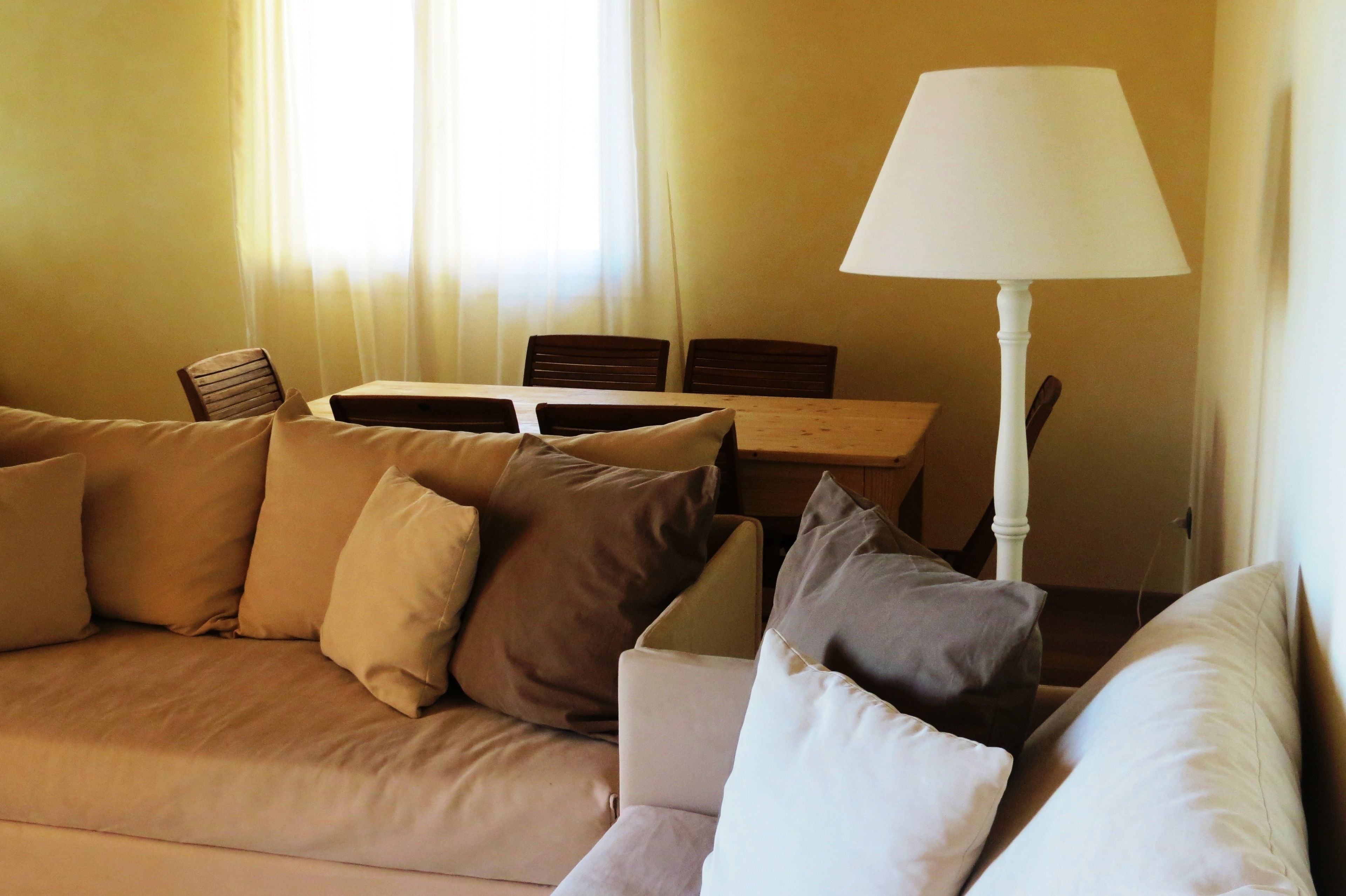 Ein Wohnzimmer mit einem beigen Sofa, einem Tisch und einer Lampe.