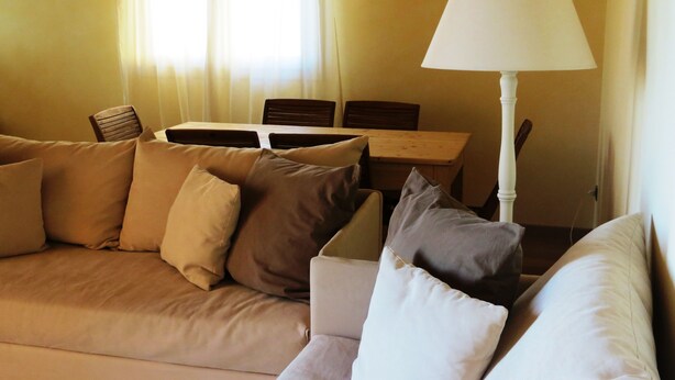 A living room with a beige sofa, a table, and a lamp. - Podere l'Agave (San Vincenzo)
