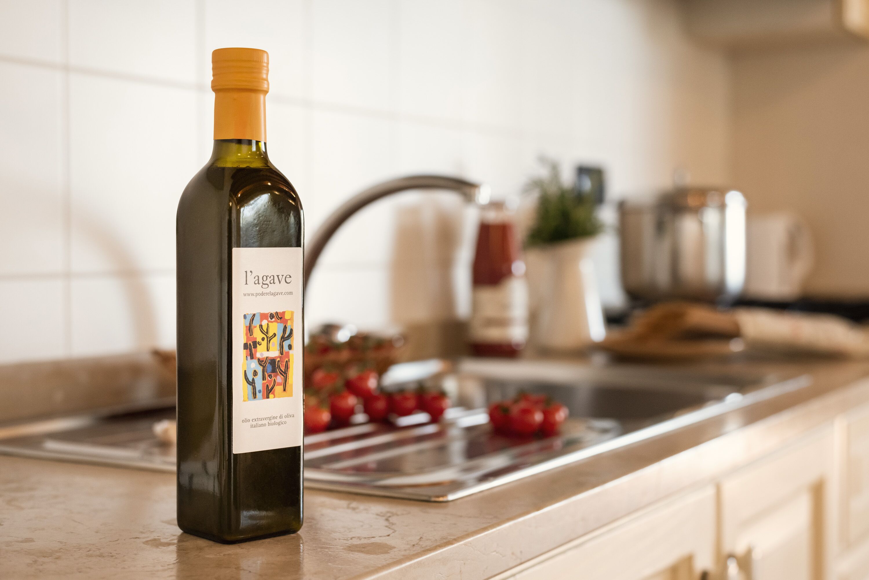 Una botella de vino sobre una encimera de cocina con un lavabo y varios utensilios de cocina al fondo.