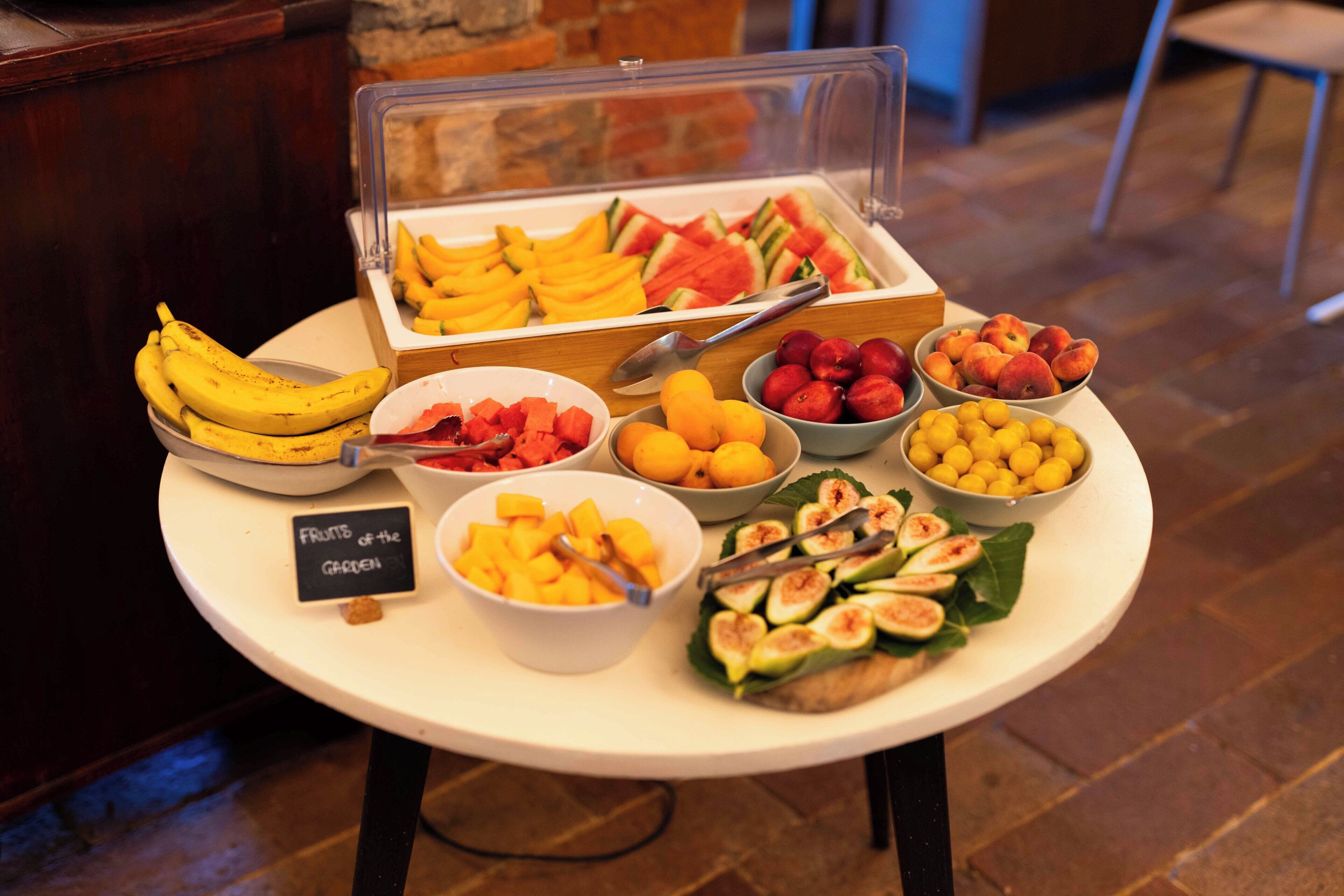 A buffet table with various fruits and a sign indicating 'FRUITS of the GARDEN.'