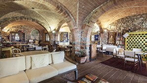 A spacious interior with a high arched brick ceiling, a white sofa, and a coffee table with magazines. - Podere l'Agave (San Vincenzo)