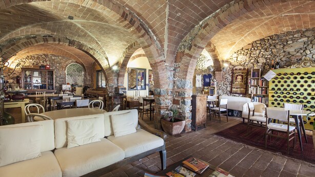 Un interior espacioso con un techo de ladrillo en arco alto, un sofá blanco y una mesa de centro con revistas.
