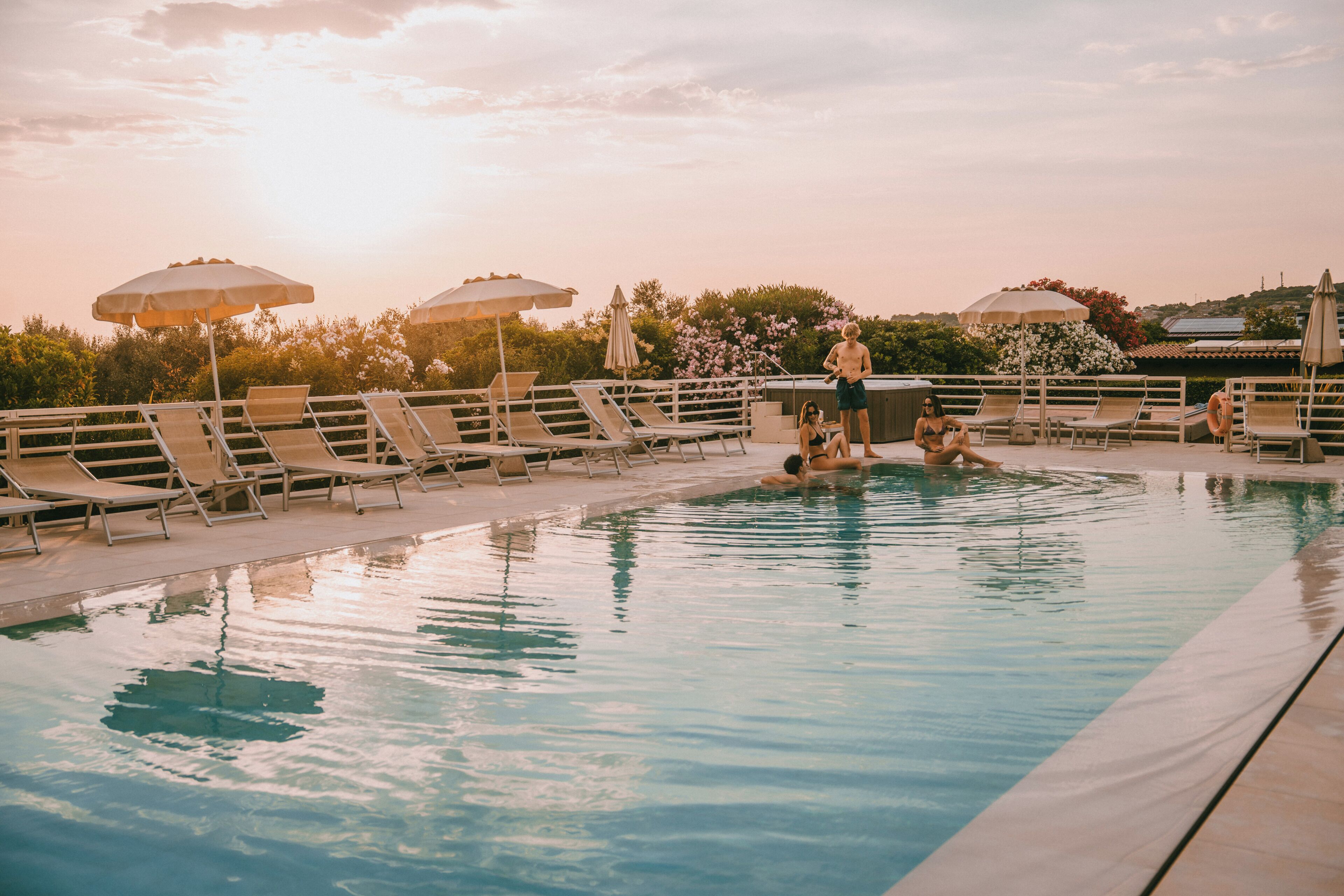 Una piscina con lettini e ombrelloni, immersa nel verde.