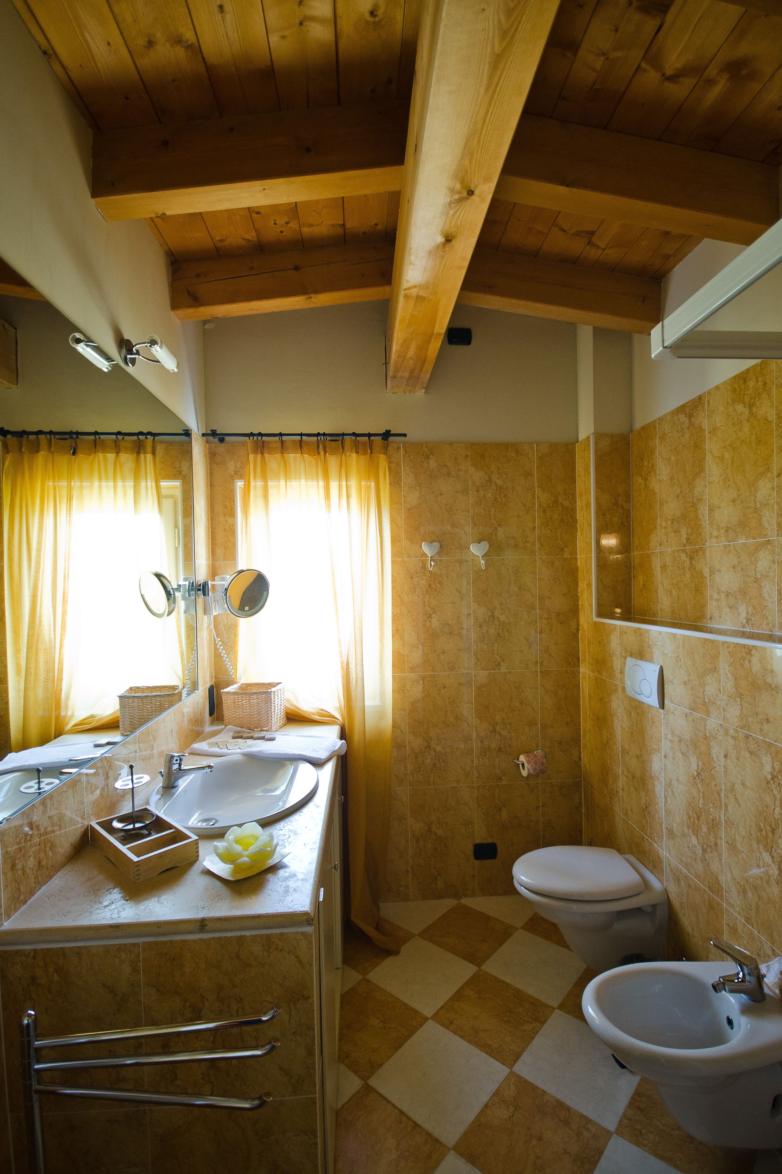 Un baño con techo de madera, suelo a cuadros, lavamanos, inodoro y bidé.