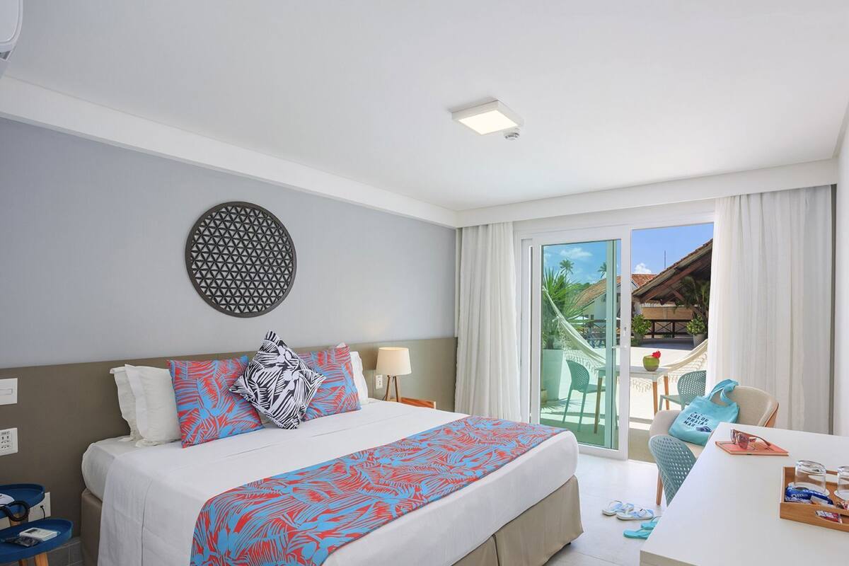Ein Hotelzimmer mit Bett, Schreibtisch, Fernseher, einer runden Wanddekoration und Blick ins Freie.