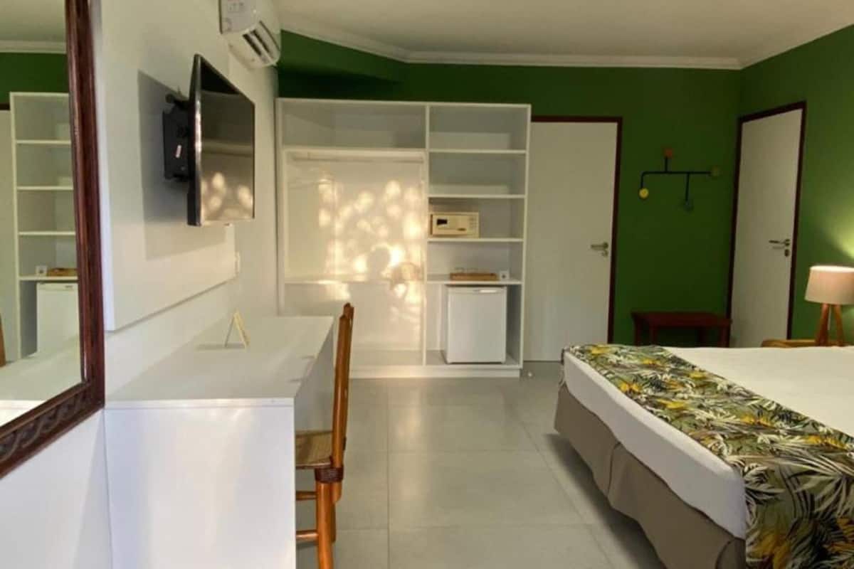 Ein Schlafzimmer mit Bett, Schreibtisch, Stuhl, Kleiderschrank und Spiegel.