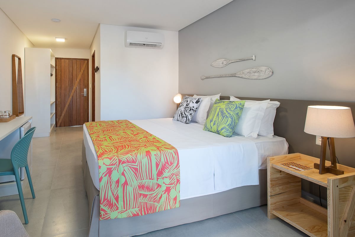 Ein Hotelzimmer mit Bett, Nachttisch, Lampe und Schreibtisch mit Stuhl.