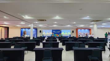 A conference room with rows of tables and chairs, a stage with a presentation screen, and a banner advertising 'Visit Colombia'.