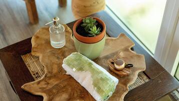 Una mesa de madera con una toalla verde, una maceta de terracota con una suculenta y una botella de vidrio.