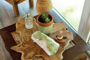 Una mesa de madera con una toalla verde, una maceta de terracota con una suculenta y una botella de vidrio.