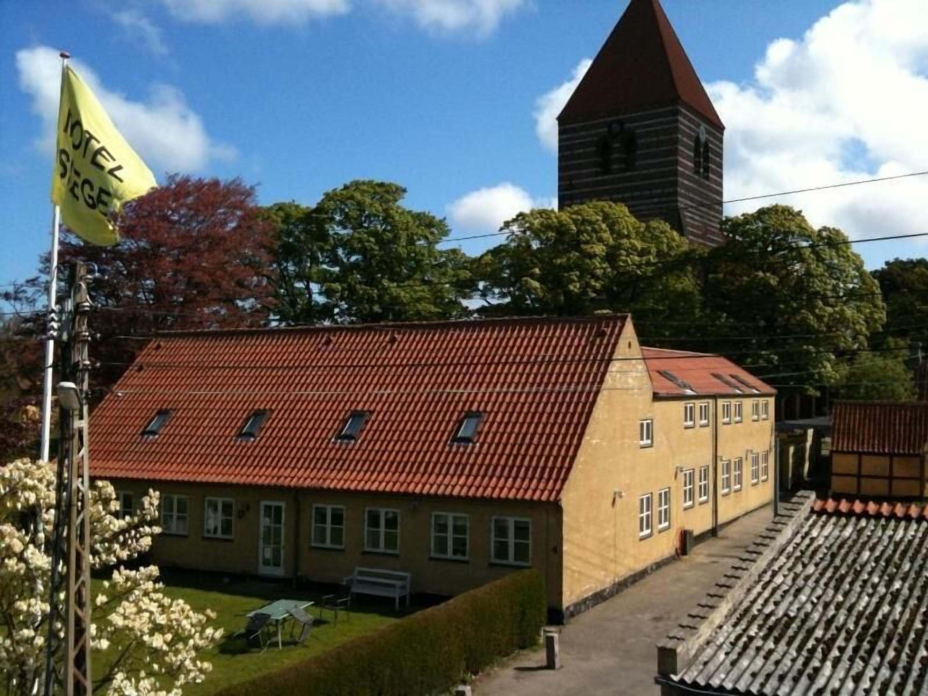 A building with a red-tiled roof and a yellow flag with text.
