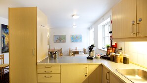 A kitchen with wooden cabinets, a sink, and a dining area with chairs and a table. - Motel Stege (Stege)