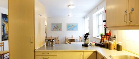 A kitchen with wooden cabinets, a sink, and a dining area with chairs and a table.