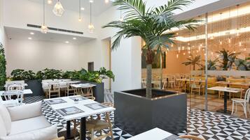 A modern indoor dining area with geometric patterned flooring, white furniture, and hanging pendant lights.