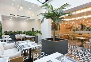 A modern indoor dining area with geometric patterned flooring, white furniture, and hanging pendant lights. - Exe Wellington (Figueira da Foz)