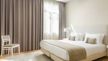 Habitación de hotel moderna con una cama grande, una silla y una mesita de noche con una lámpara.