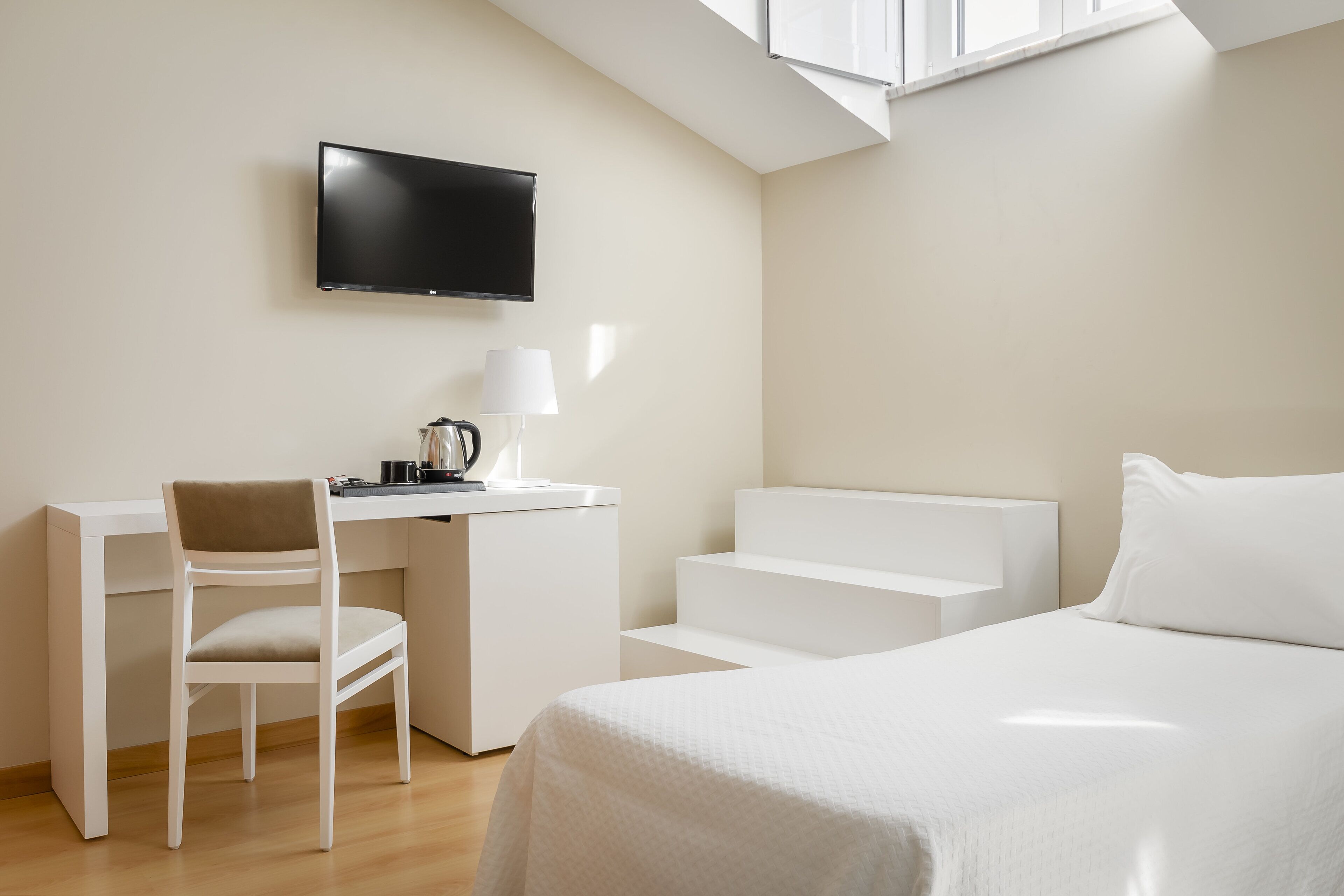 Une chambre d’hôtel moderne équipée d’un lit, d’un bureau avec une chaise, d’une télévision et d’un escalier.